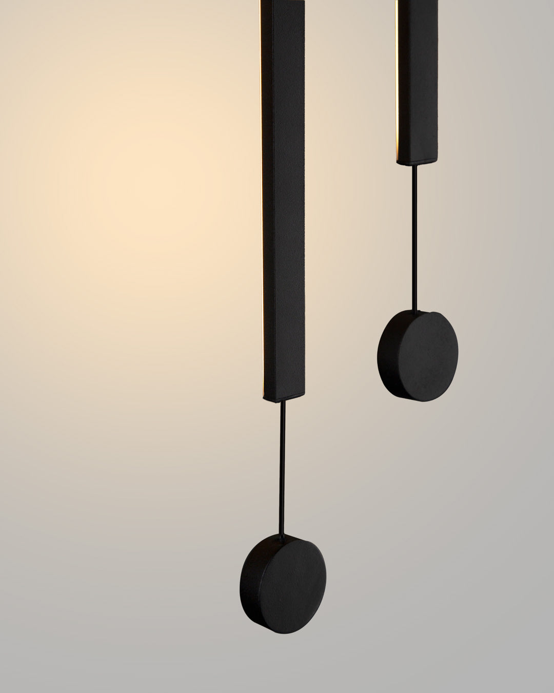 Two lines pendant light with slim vertical black rods creating warm ambient lighting / إضاءة معلقة بخطين بتصميم طولي نحيف باللون الأسود تضيف إضاءة دافئة وعصرية