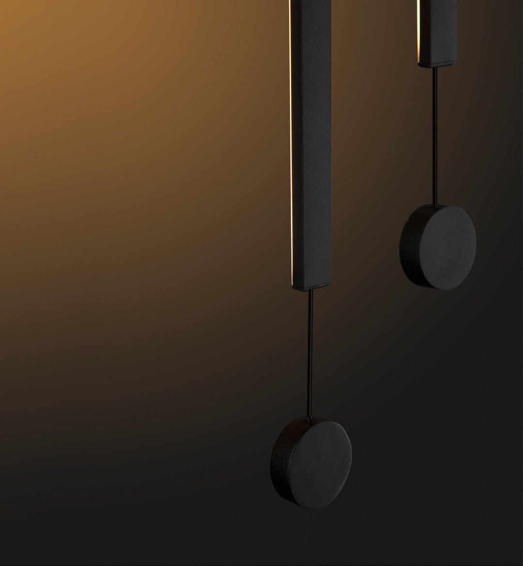 Two lines pendant light with slim vertical black rods creating warm ambient lighting / إضاءة معلقة بخطين بتصميم طولي نحيف باللون الأسود تضيف إضاءة دافئة وعصرية